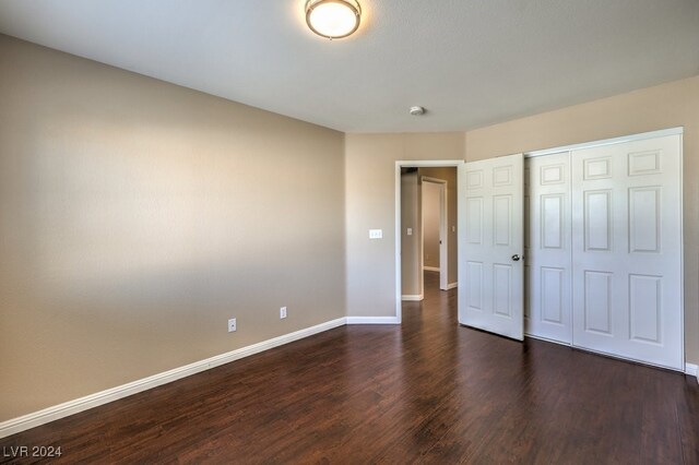 unfurnished bedroom with a closet and dark hardwood / wood-style flooring