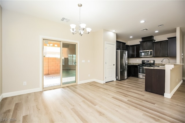 kitchen featuring light stone countertops, light hardwood / wood-style flooring, pendant lighting, a chandelier, and appliances with stainless steel finishes