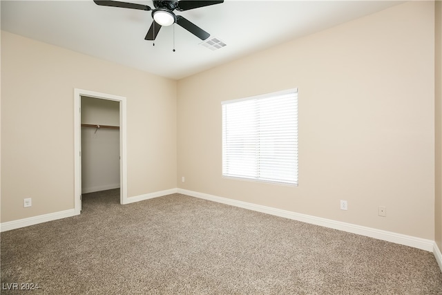 unfurnished bedroom with carpet, ceiling fan, a spacious closet, and a closet