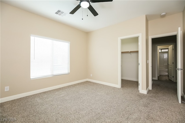 unfurnished bedroom with ceiling fan, light colored carpet, a spacious closet, and a closet