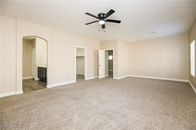 unfurnished bedroom with connected bathroom, ceiling fan, carpet floors, a walk in closet, and a closet