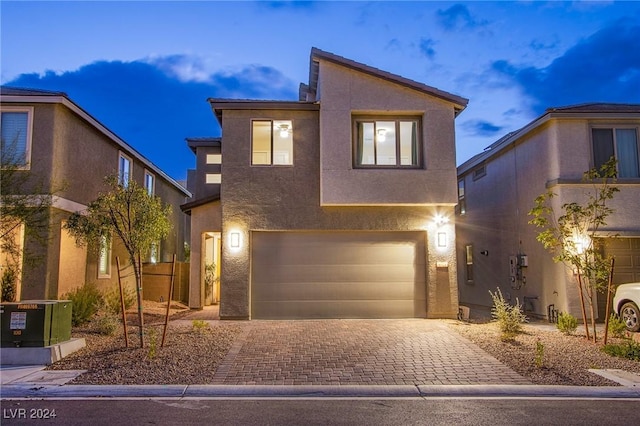 modern home featuring decorative driveway, central AC, an attached garage, and stucco siding