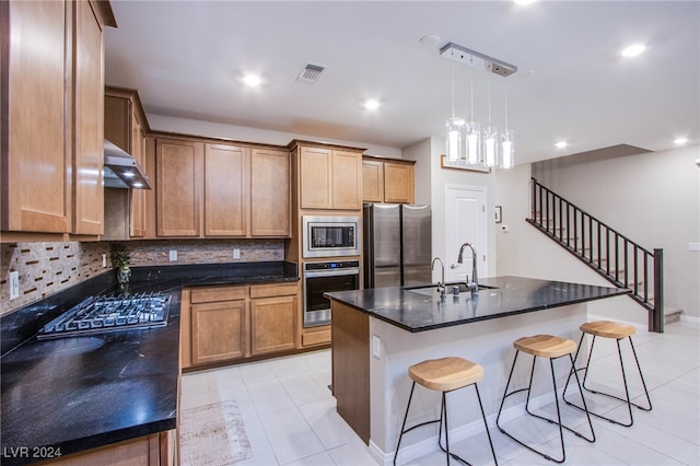 kitchen featuring appliances with stainless steel finishes, tasteful backsplash, a kitchen island with sink, sink, and pendant lighting