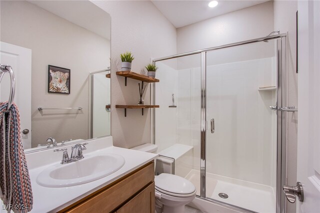 bathroom with a shower with door, vanity, and toilet