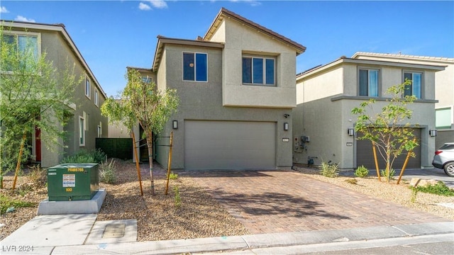 contemporary house with decorative driveway, a garage, and stucco siding