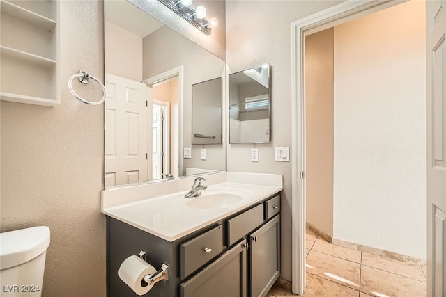 bathroom with toilet, vanity, and tile patterned floors