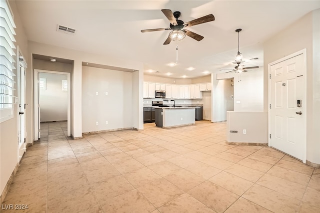 kitchen with ceiling fan, a center island, white cabinets, and sink