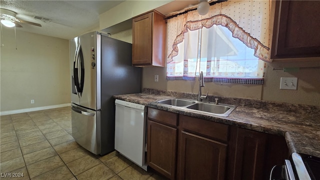 kitchen featuring dishwasher, sink, ceiling fan, light tile patterned floors, and stainless steel range