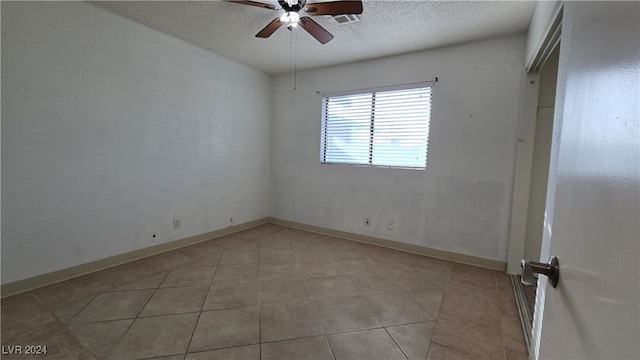 spare room with ceiling fan, light tile patterned flooring, and a textured ceiling