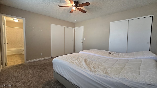 carpeted bedroom featuring a textured ceiling, ceiling fan, multiple closets, and connected bathroom