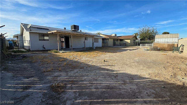 rear view of property with central air condition unit and solar panels