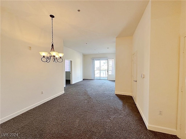 empty room with baseboards, dark colored carpet, and a notable chandelier