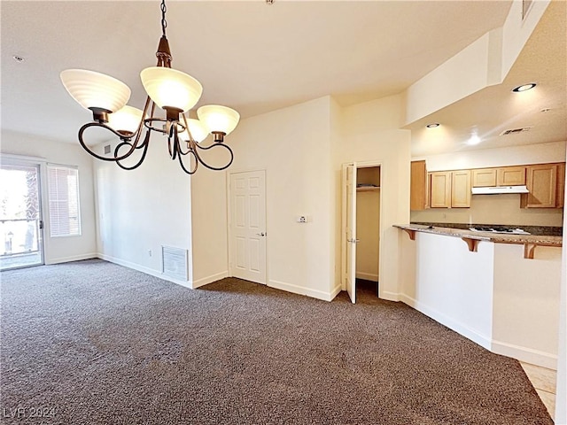 unfurnished dining area with baseboards, visible vents, dark colored carpet, and a notable chandelier