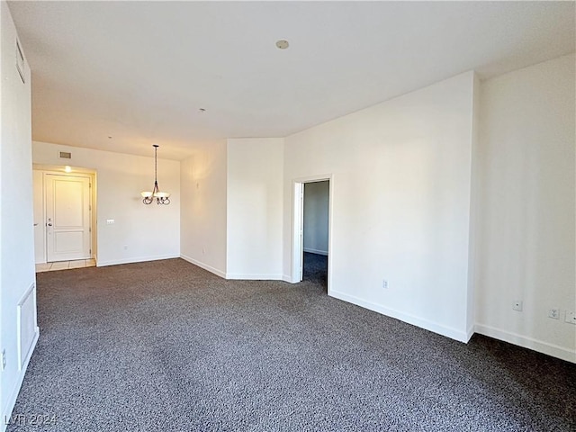 spare room featuring an inviting chandelier, baseboards, visible vents, and dark carpet