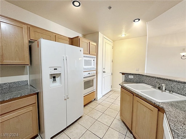 kitchen with white appliances, light tile patterned floors, light brown cabinets, a sink, and recessed lighting