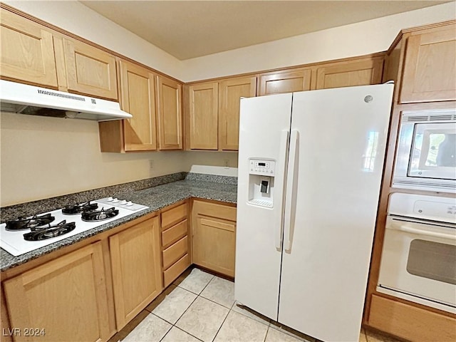 kitchen featuring white appliances, light brown cabinets, under cabinet range hood, and light tile patterned floors