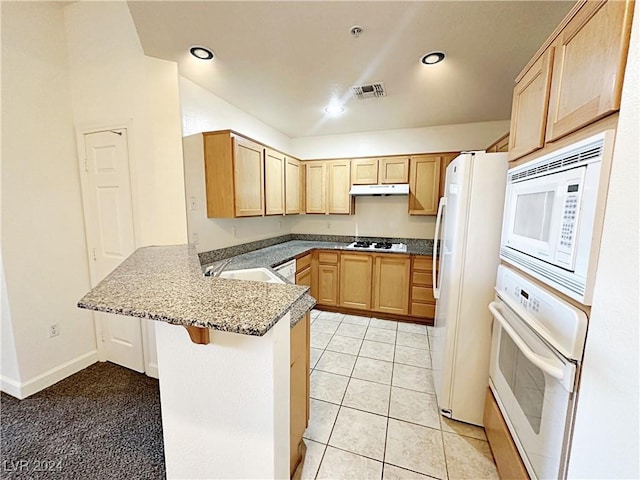 kitchen with white appliances, visible vents, a peninsula, light brown cabinets, and a sink