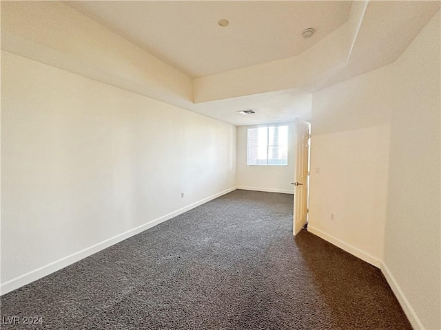 unfurnished room with visible vents, baseboards, and dark colored carpet