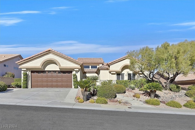 mediterranean / spanish house with a tile roof, driveway, an attached garage, and stucco siding