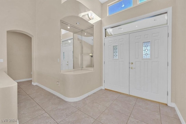 entrance foyer with arched walkways, light tile patterned floors, and baseboards