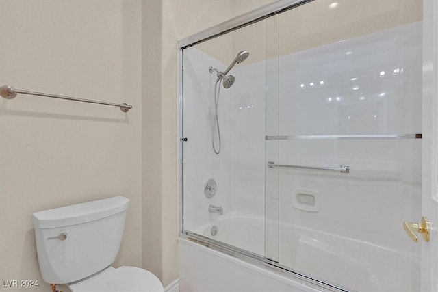 bathroom with toilet and shower / bath combination with glass door