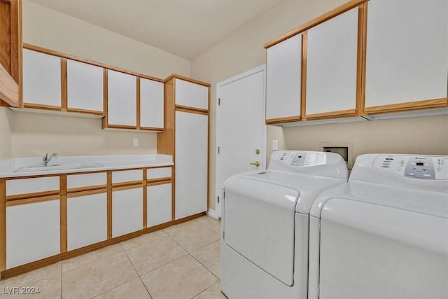 clothes washing area featuring light tile patterned floors, washing machine and dryer, a sink, and cabinet space