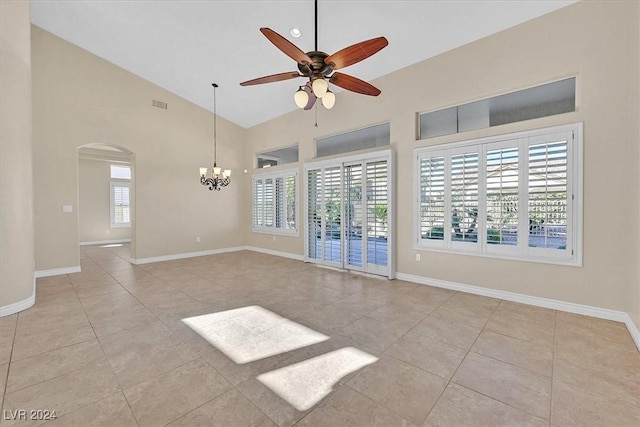 unfurnished living room featuring ceiling fan with notable chandelier, high vaulted ceiling, arched walkways, visible vents, and baseboards