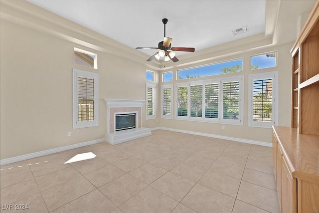 unfurnished living room with baseboards, a raised ceiling, light tile patterned floors, visible vents, and ceiling fan