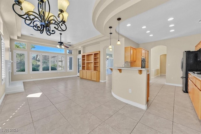 kitchen featuring a tray ceiling, a kitchen breakfast bar, arched walkways, and oven