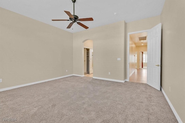unfurnished bedroom featuring arched walkways, a ceiling fan, visible vents, light carpet, and baseboards