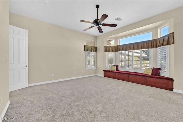 carpeted spare room with visible vents, baseboards, and ceiling fan