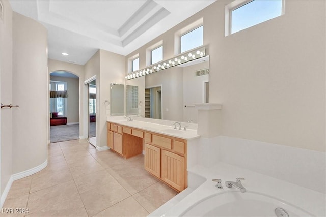 bathroom with a raised ceiling, a bath, a sink, and tile patterned flooring