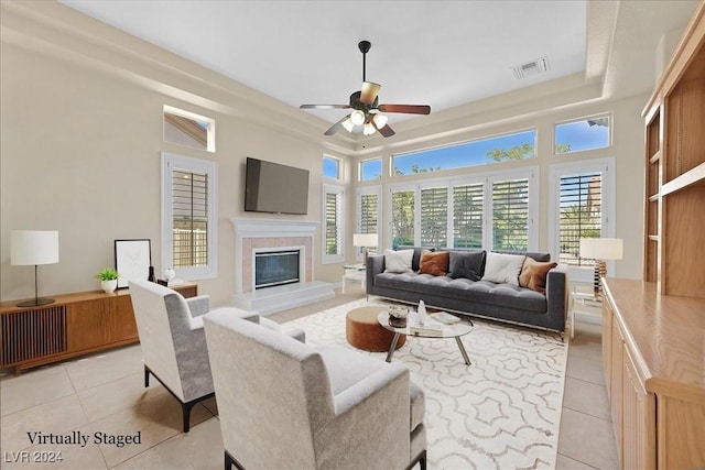living area featuring light tile patterned floors, visible vents, a ceiling fan, and a raised ceiling
