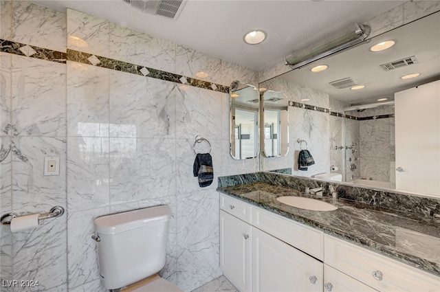 bathroom with a shower, vanity, tile walls, and toilet