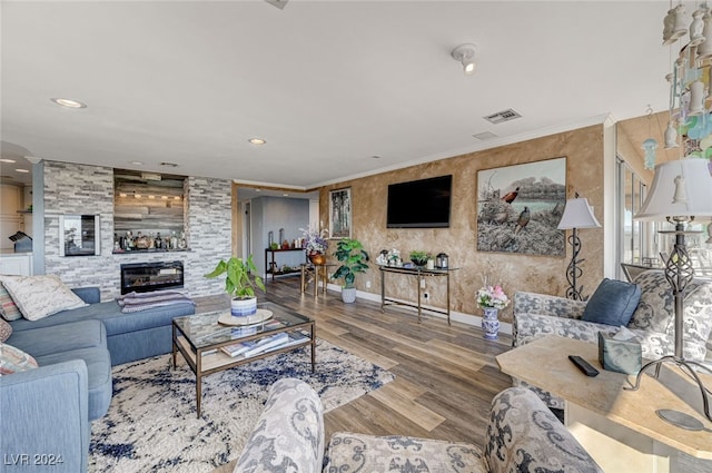 living room with hardwood / wood-style flooring, a large fireplace, and crown molding