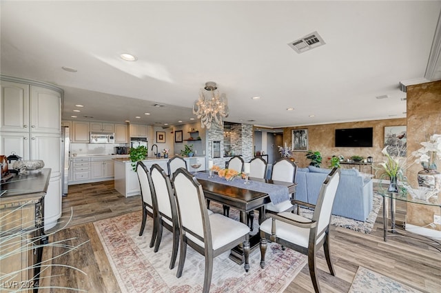 dining area with crown molding, sink, a notable chandelier, and light wood-type flooring