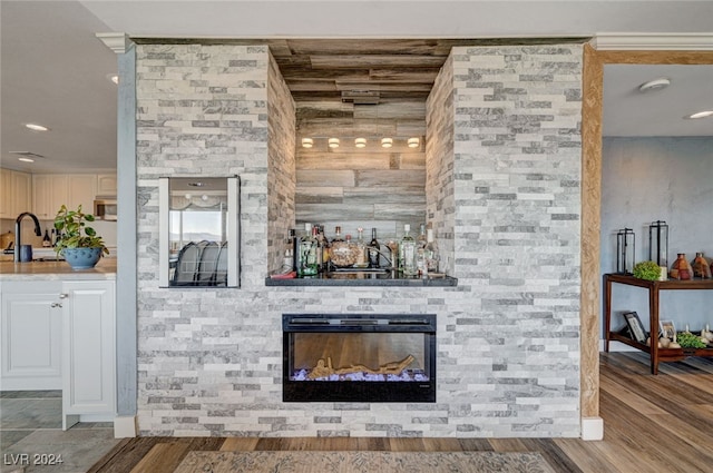 bar with a fireplace and hardwood / wood-style floors