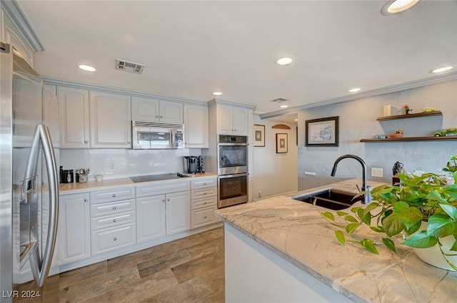 kitchen featuring light stone countertops, appliances with stainless steel finishes, tasteful backsplash, sink, and white cabinets