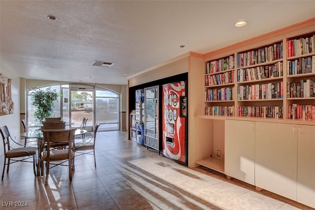 dining space featuring crown molding, light tile patterned flooring, and a textured ceiling