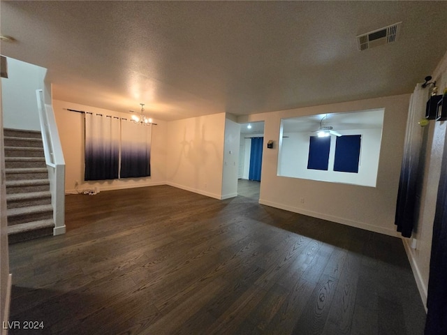 unfurnished living room featuring a textured ceiling, a chandelier, and dark hardwood / wood-style floors