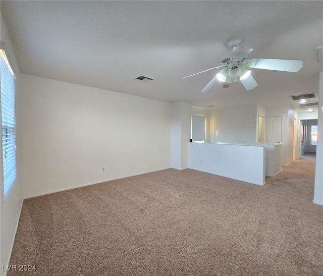 spare room featuring light colored carpet, plenty of natural light, and ceiling fan