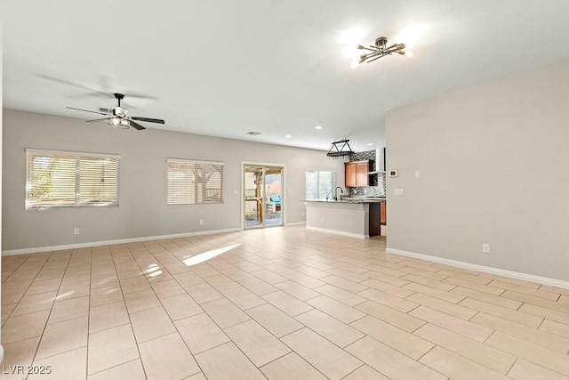 unfurnished living room featuring light tile patterned flooring, sink, and ceiling fan