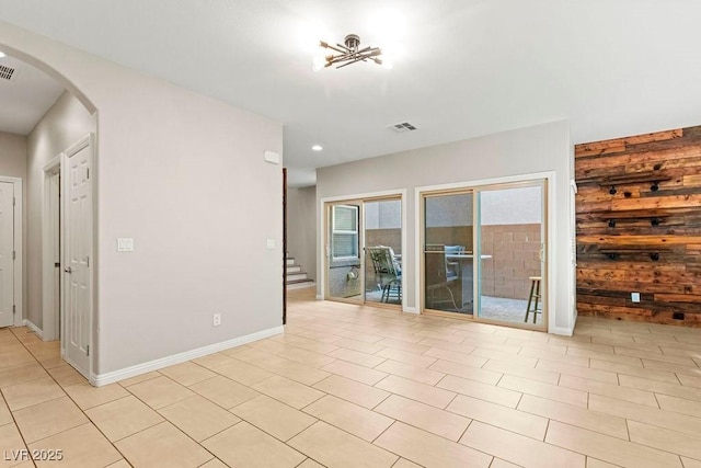 tiled empty room featuring wood walls