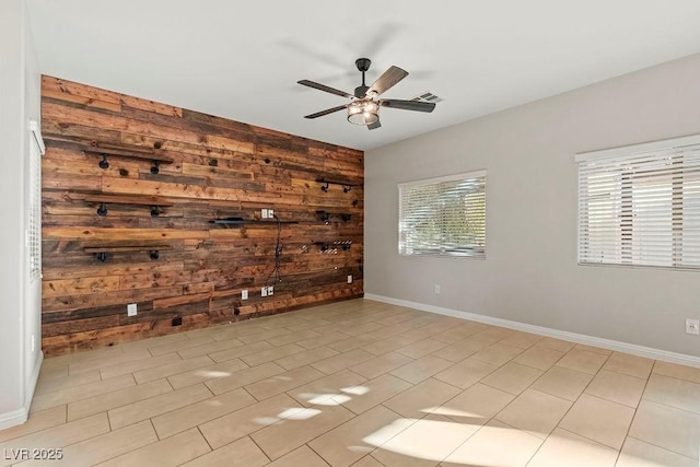 spare room with ceiling fan and wooden walls