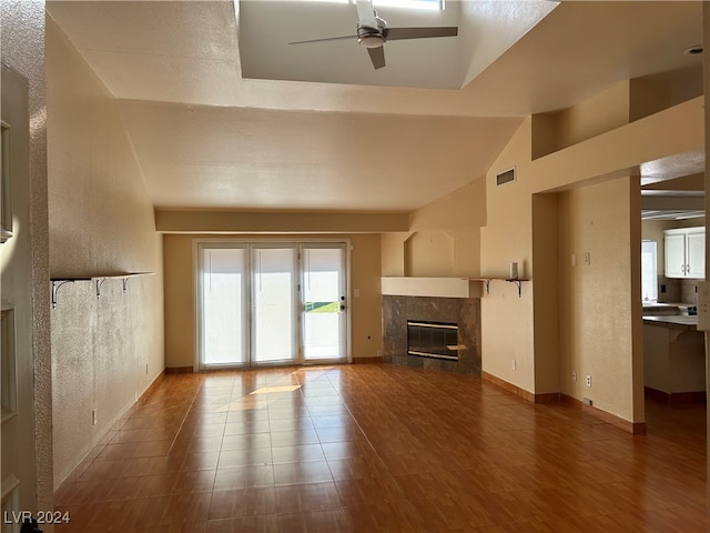 unfurnished living room with vaulted ceiling, hardwood / wood-style flooring, ceiling fan, a fireplace, and a textured ceiling