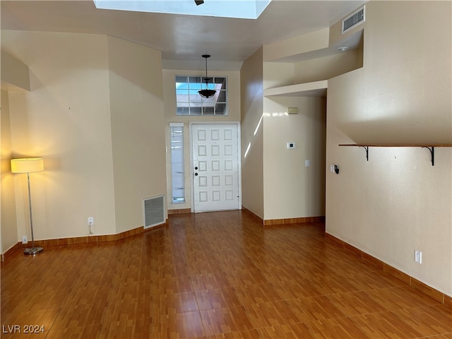 interior space featuring wood-type flooring, a skylight, and a high ceiling