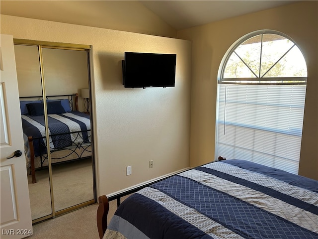 carpeted bedroom featuring vaulted ceiling and a closet