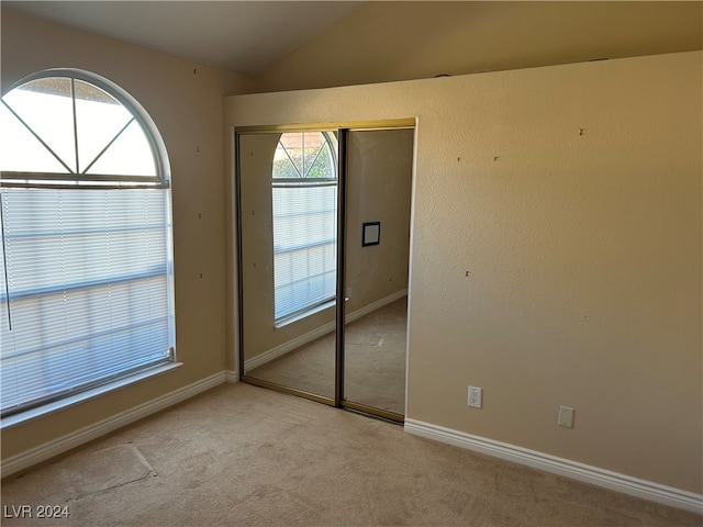 interior space with light colored carpet, lofted ceiling, and a closet