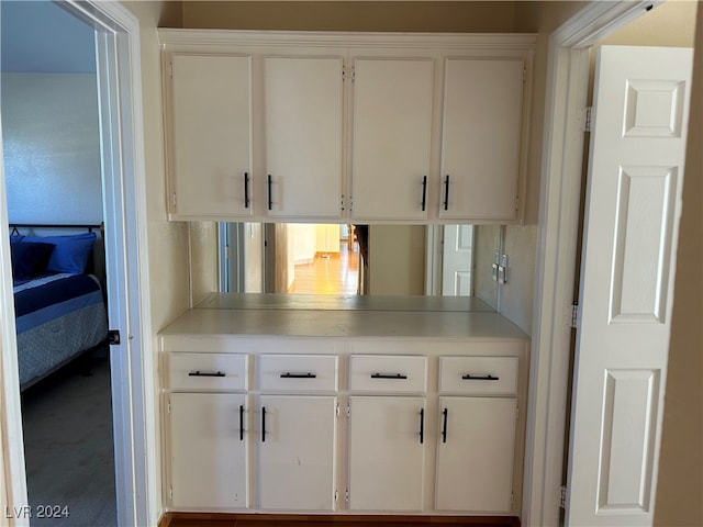 kitchen featuring carpet and white cabinetry