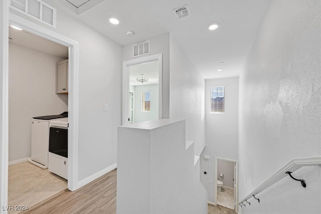 hall with light hardwood / wood-style floors and separate washer and dryer